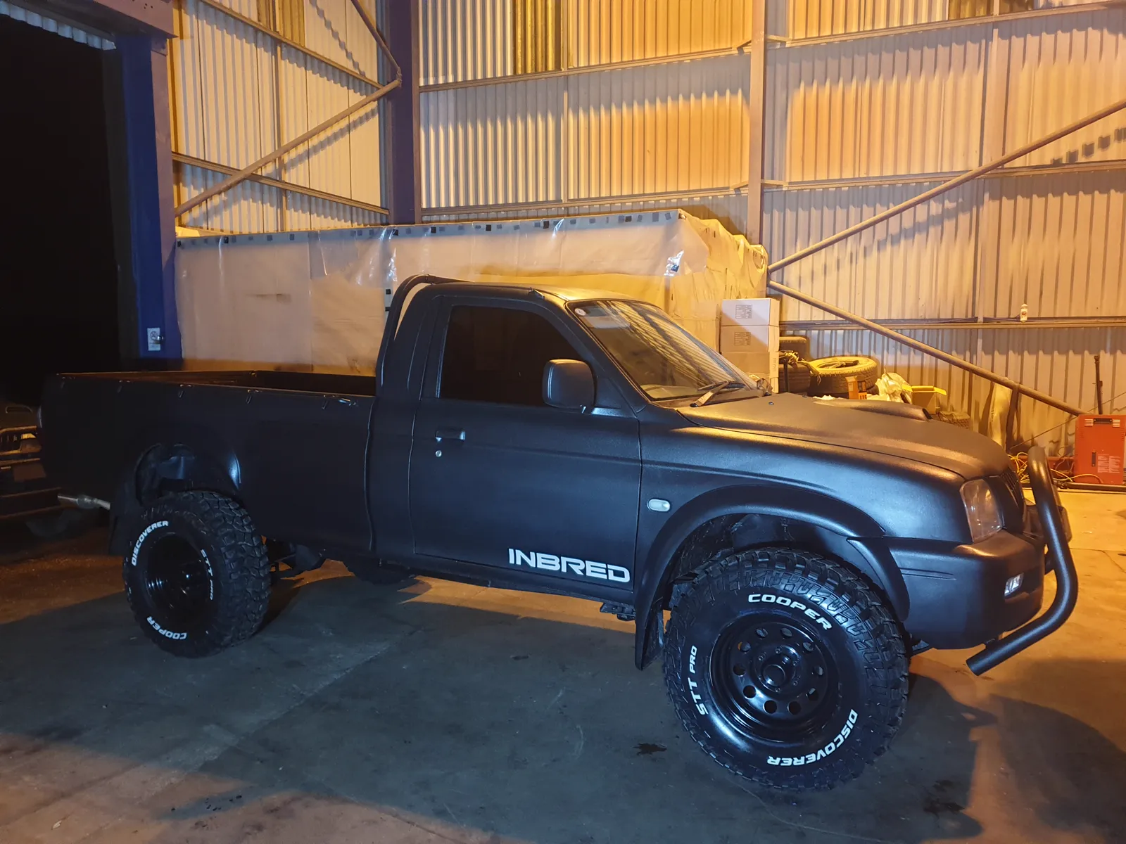 The Inbred Edition, a matte black single cab L200 with the name on the tub, in the STC workshop at night