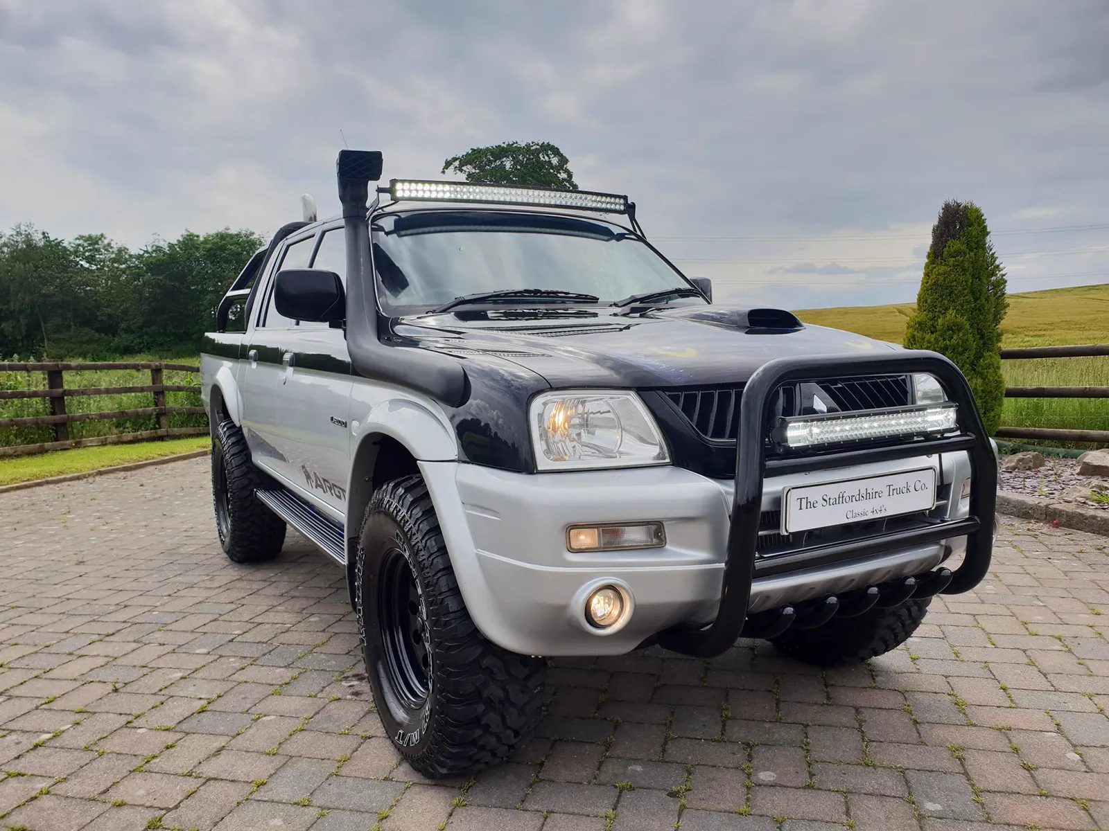 The STC Wolf Edition, silver over black with a bull bar, snorkel and light bar, on a block-paved drive