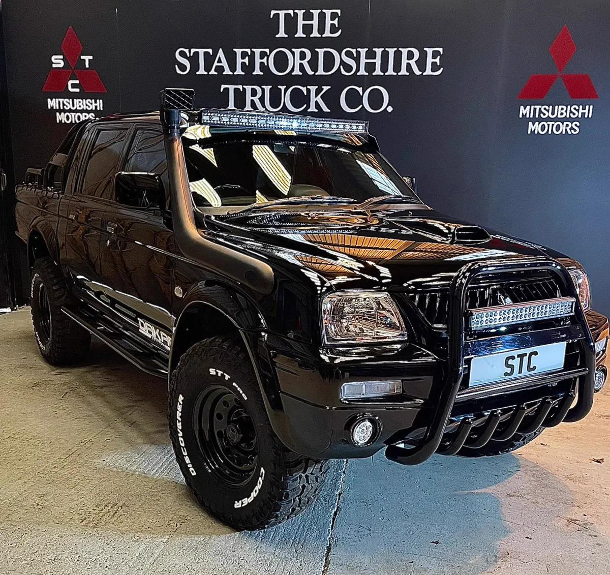 A black STC Dakar Edition L200 with bull bar and light bar in the studio