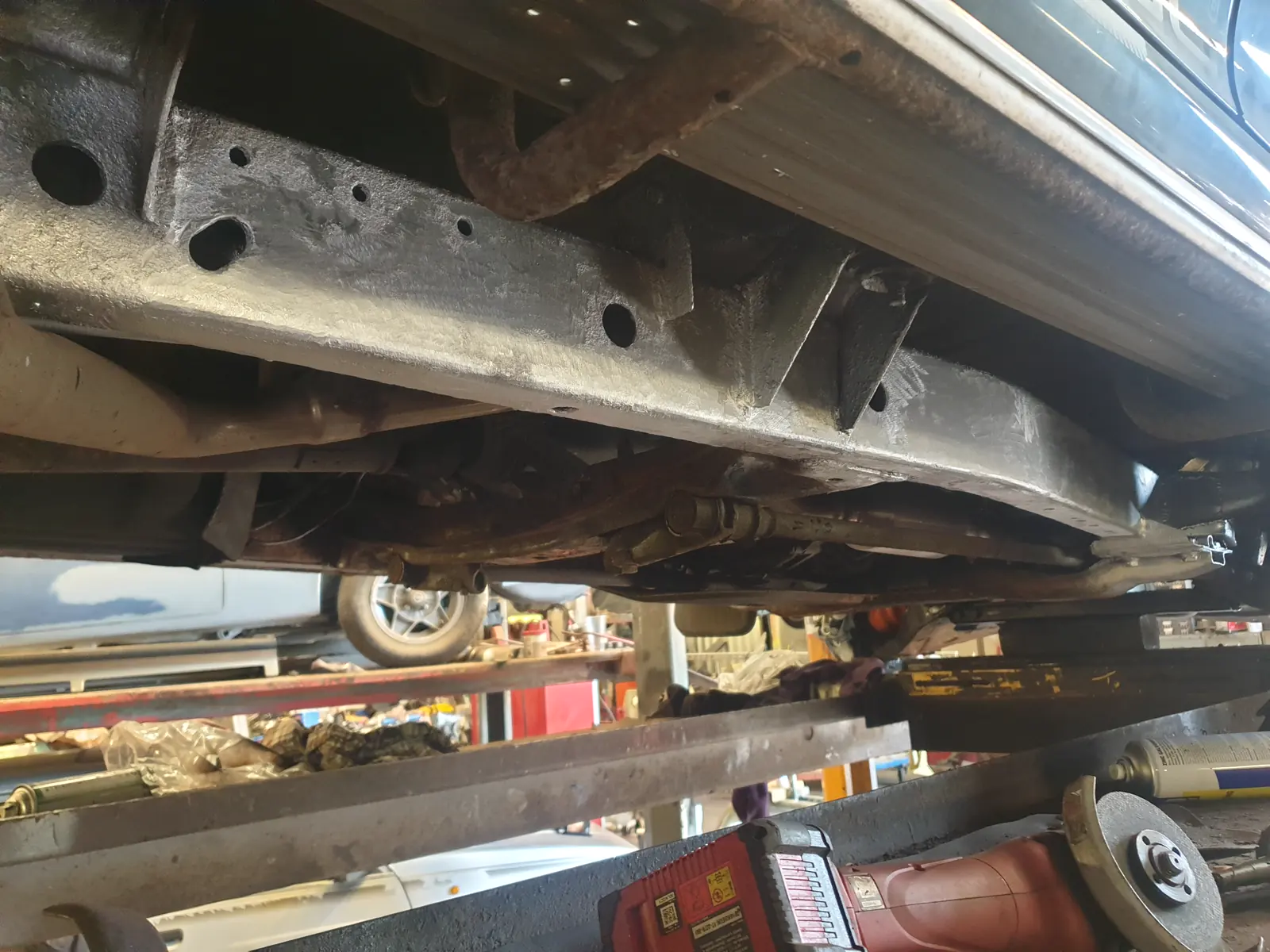 The bare underside and chassis of a Mitsubishi L200 K74 on a ramp before treatment