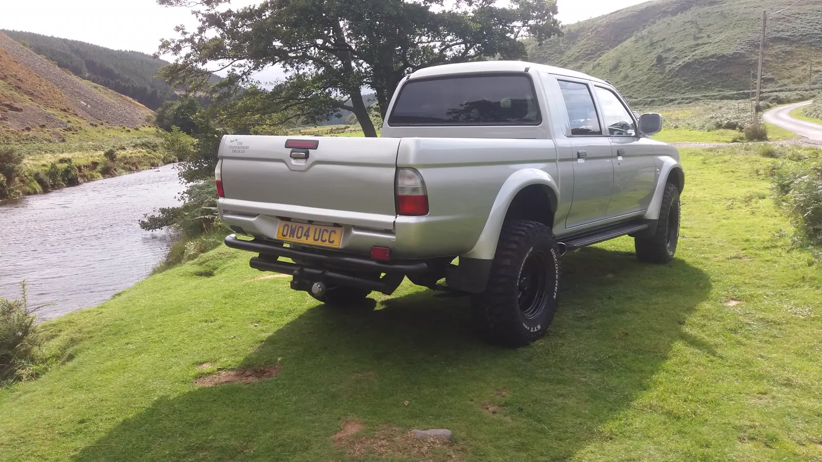 Rob&rsquo;s silver L200 after its rebuild, on grass with the hills behind