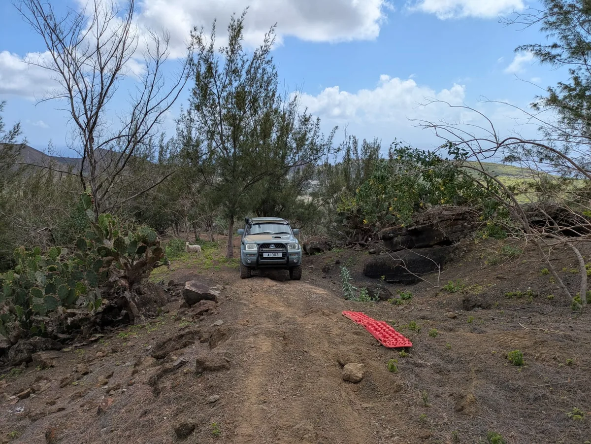 The Dakar on a rough dirt trail, a red recovery board in front of it