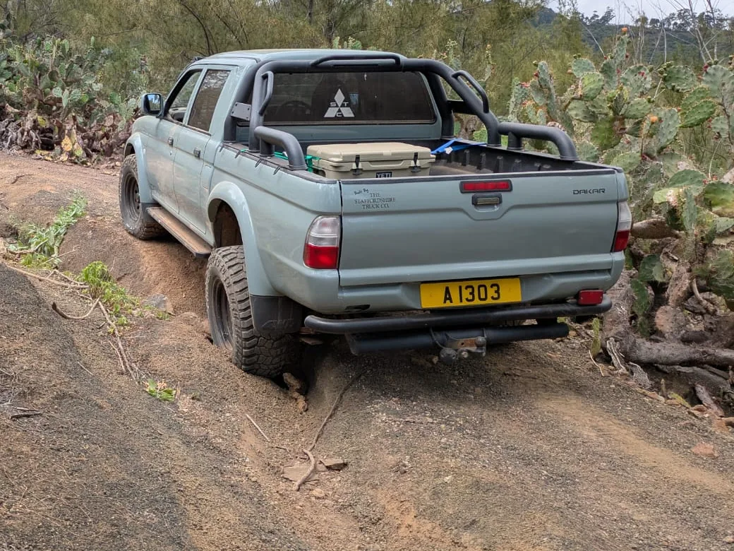 The Dakar in a rutted woodland track, seen from behind